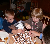 Kids decorating cookies and their mouths with sugar frosting