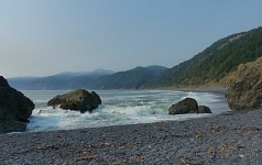 Na Black Sand Beach je vidět kouřový příklop nad vzálenými kopci.